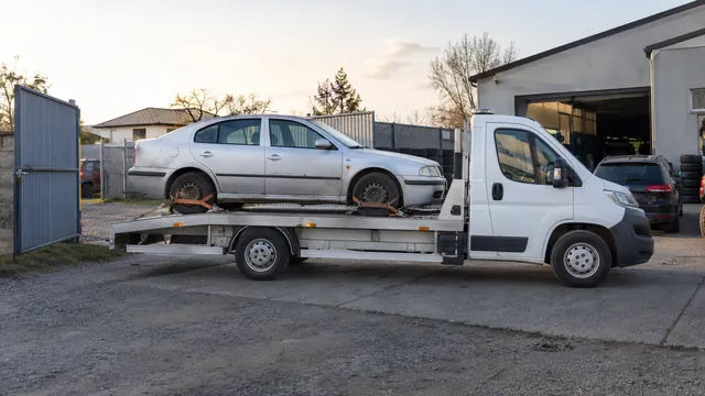 Bílý odtahový vůz s upevněným vozidlem Škoda na hliníkové plošině
