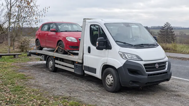 Bílý odtahový vůz s upevněným vozidlem Škoda na hliníkové plošině