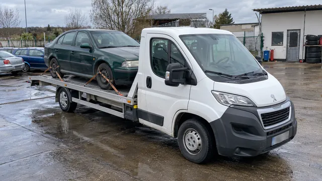 Bílý odtahový vůz s upevněným vozidlem Škoda na hliníkové plošině
