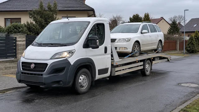 Bílý odtahový vůz s upevněným vozidlem Škoda na hliníkové plošině