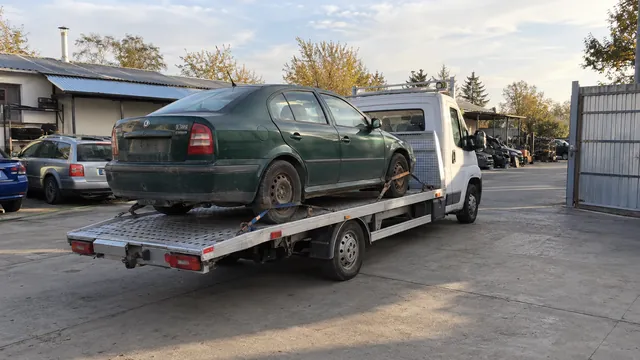 Bílý odtahový vůz s upevněným vozidlem Škoda na hliníkové plošině