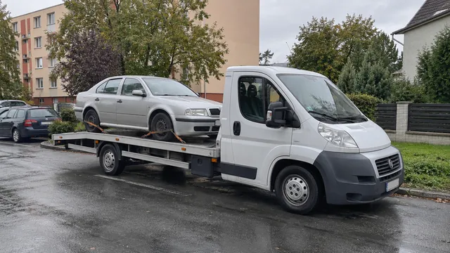 Bílý odtahový vůz s upevněným vozidlem Škoda na hliníkové plošině