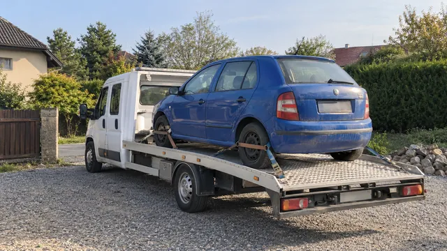 Bílý odtahový vůz s upevněným vozidlem Škoda na hliníkové plošině