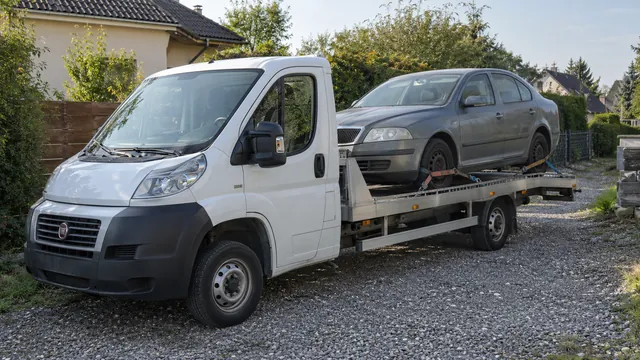 Bílý odtahový vůz s upevněným vozidlem Škoda na hliníkové plošině
