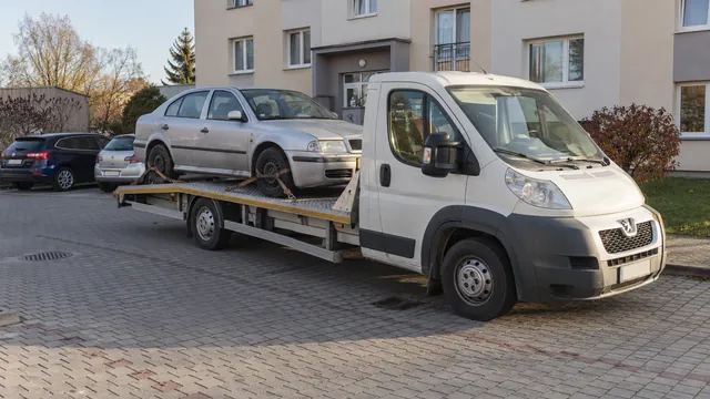 Bílý odtahový vůz s upevněným vozidlem Škoda na hliníkové plošině