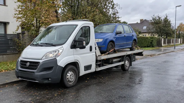 Bílý odtahový vůz s upevněným vozidlem Škoda na hliníkové plošině