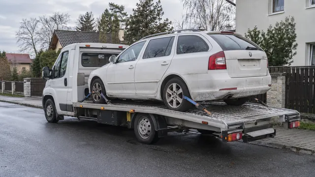 Bílý odtahový vůz s upevněným vozidlem Škoda na hliníkové plošině