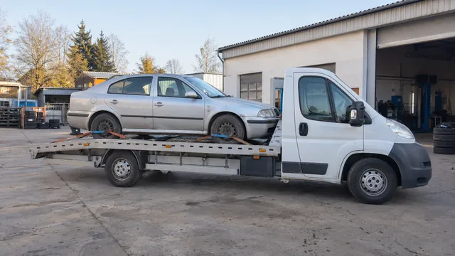 Bílý odtahový vůz s upevněným vozidlem Škoda na hliníkové plošině