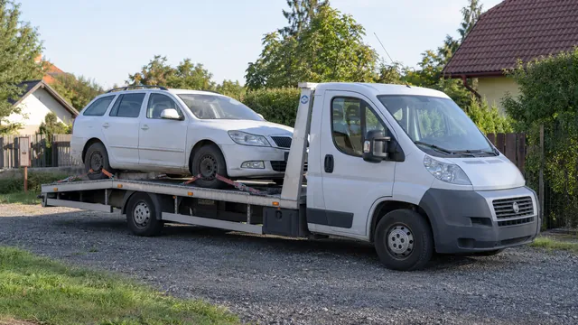 Bílý odtahový vůz s upevněným vozidlem Škoda na hliníkové plošině