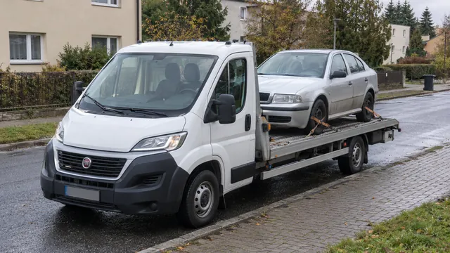Bílý odtahový vůz s upevněným vozidlem Škoda na hliníkové plošině