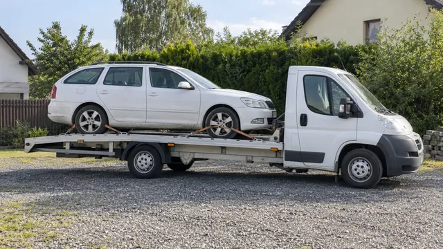 Bílý odtahový vůz s upevněným vozidlem Škoda na hliníkové plošině