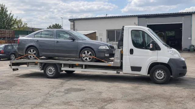 Bílý odtahový vůz s upevněným vozidlem Škoda na hliníkové plošině