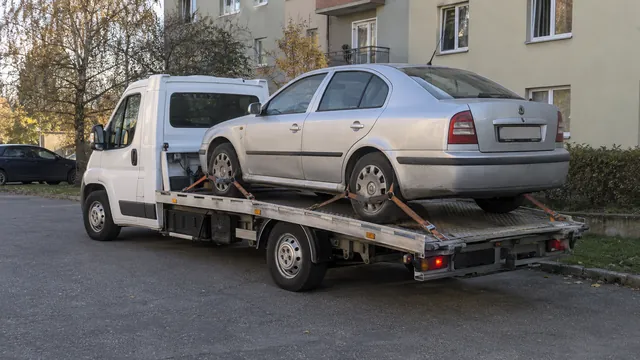 Bílý odtahový vůz s upevněným vozidlem Škoda na hliníkové plošině