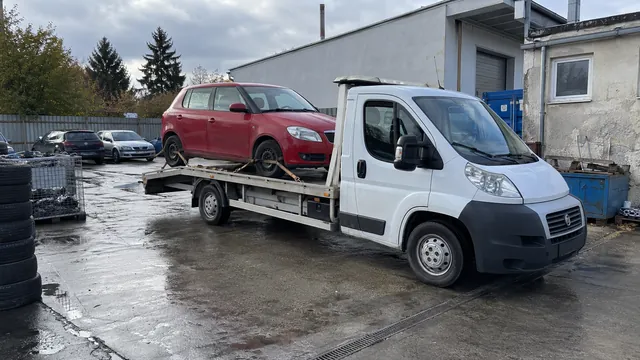 Bílý odtahový vůz s upevněným vozidlem Škoda na hliníkové plošině