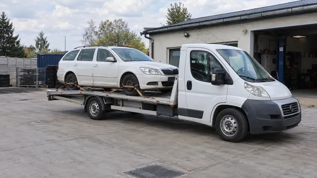 Bílý odtahový vůz s upevněným vozidlem Škoda na hliníkové plošině