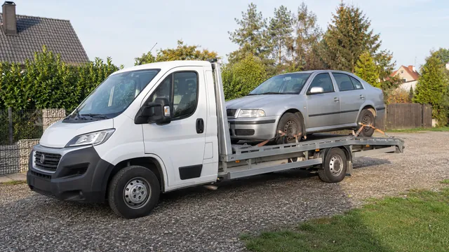 Bílý odtahový vůz s upevněným vozidlem Škoda na hliníkové plošině