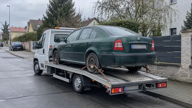 Bílý odtahový vůz s upevněným vozidlem Škoda na hliníkové plošině
