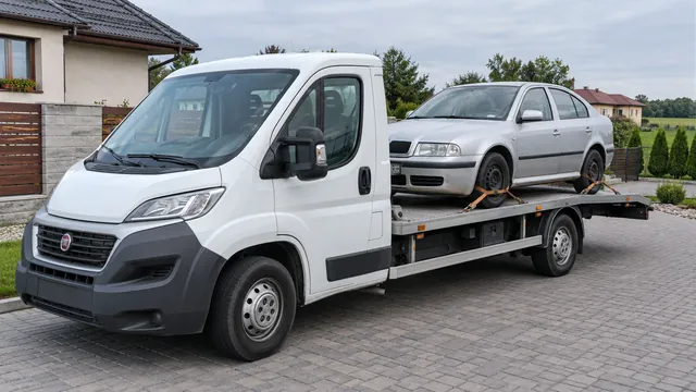 Bílý odtahový vůz s upevněným vozidlem Škoda na hliníkové plošině
