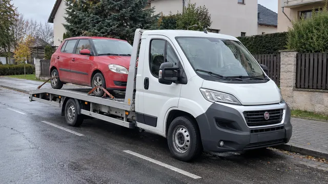 Bílý odtahový vůz s upevněným vozidlem Škoda na hliníkové plošině