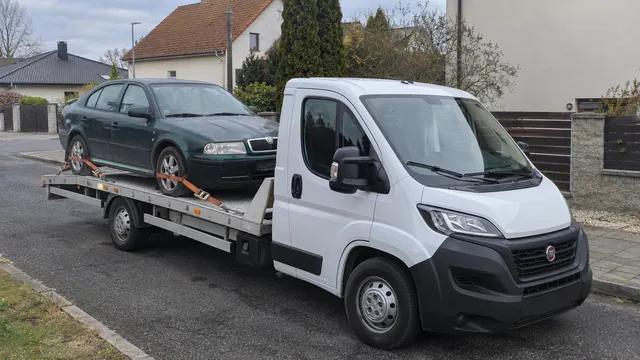 Bílý odtahový vůz s upevněným vozidlem Škoda na hliníkové plošině