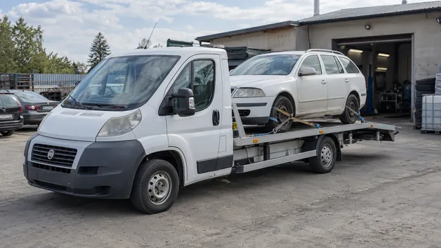 Bílý odtahový vůz s upevněným vozidlem Škoda na hliníkové plošině