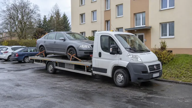 Bílý odtahový vůz s upevněným vozidlem Škoda na hliníkové plošině