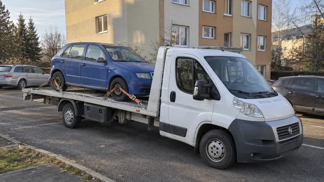 Bílý odtahový vůz s upevněným vozidlem Škoda na hliníkové plošině