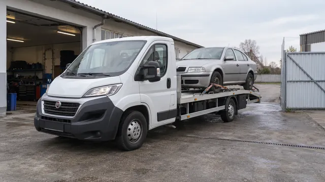 Bílý odtahový vůz s upevněným vozidlem Škoda na hliníkové plošině