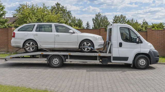Bílý odtahový vůz s upevněným vozidlem Škoda na hliníkové plošině