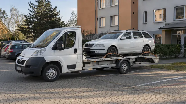 Bílý odtahový vůz s upevněným vozidlem Škoda na hliníkové plošině