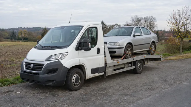 Bílý odtahový vůz s upevněným vozidlem Škoda na hliníkové plošině