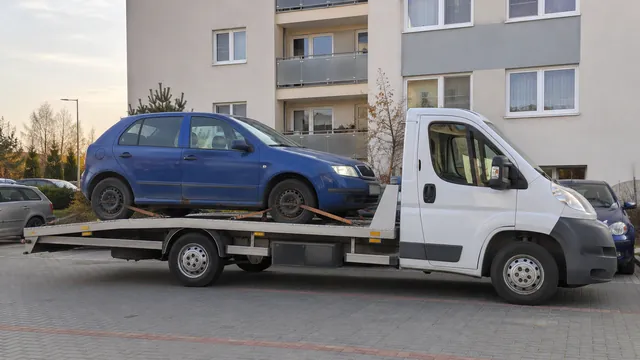 Bílý odtahový vůz s upevněným vozidlem Škoda na hliníkové plošině