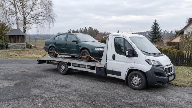 Bílý odtahový vůz s upevněným vozidlem Škoda na hliníkové plošině