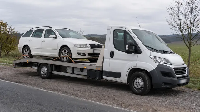 Bílý odtahový vůz s upevněným vozidlem Škoda na hliníkové plošině