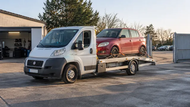 Bílý odtahový vůz s upevněným vozidlem Škoda na hliníkové plošině