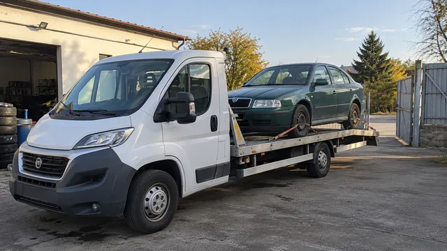 Bílý odtahový vůz s upevněným vozidlem Škoda na hliníkové plošině