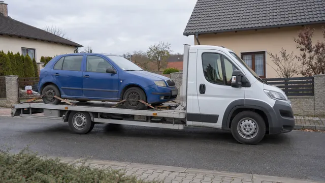 Bílý odtahový vůz s upevněným vozidlem Škoda na hliníkové plošině