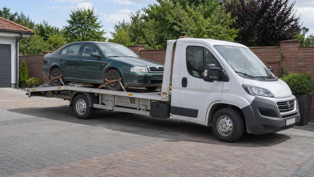 Bílý odtahový vůz s upevněným vozidlem Škoda na hliníkové plošině