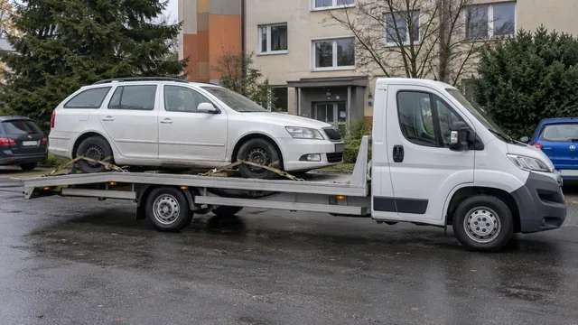 Bílý odtahový vůz s upevněným vozidlem Škoda na hliníkové plošině