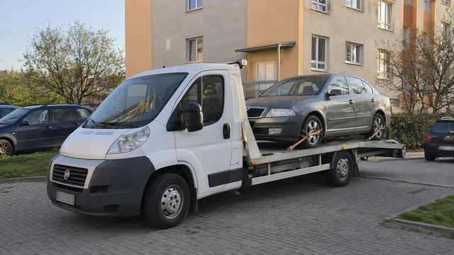 Bílý odtahový vůz s upevněným vozidlem Škoda na hliníkové plošině