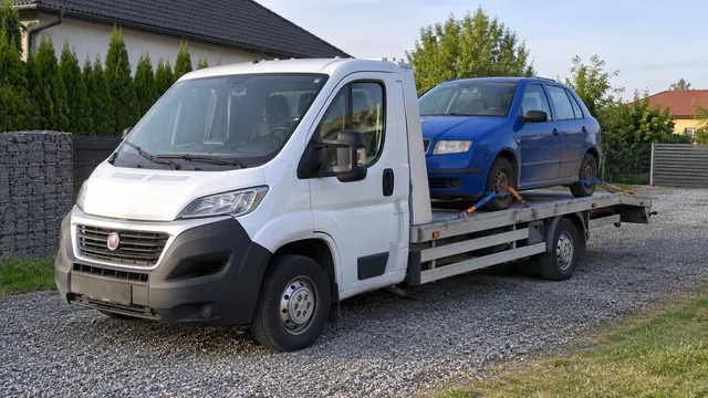 Bílý odtahový vůz s upevněným vozidlem Škoda na hliníkové plošině