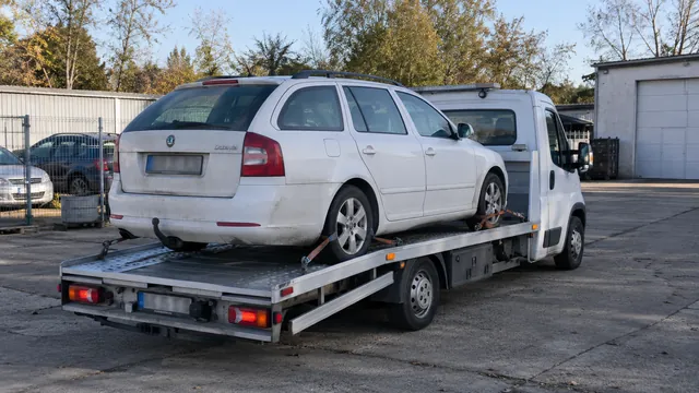 Bílý odtahový vůz s upevněným vozidlem Škoda na hliníkové plošině
