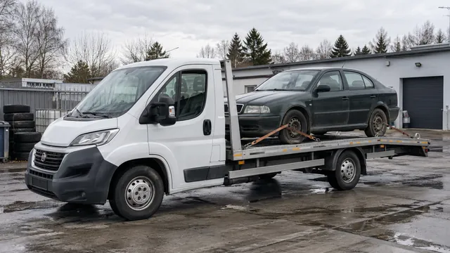 Bílý odtahový vůz s upevněným vozidlem Škoda na hliníkové plošině