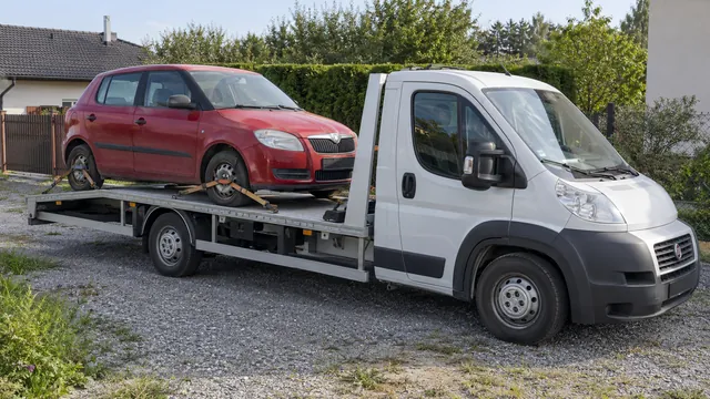Bílý odtahový vůz s upevněným vozidlem Škoda na hliníkové plošině
