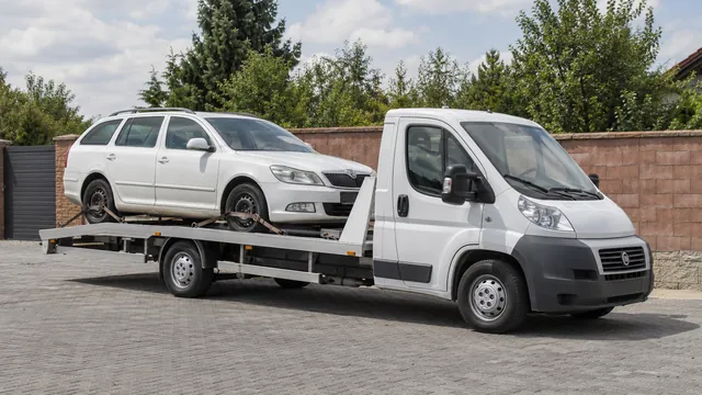 Bílý odtahový vůz s upevněným vozidlem Škoda na hliníkové plošině