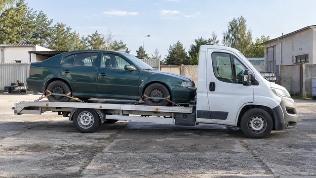 Bílý odtahový vůz s upevněným vozidlem Škoda na hliníkové plošině