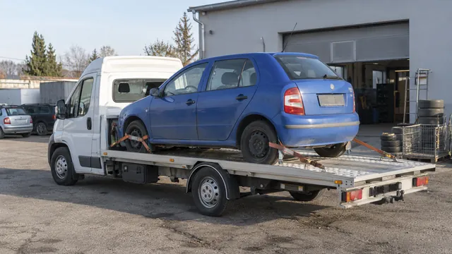 Bílý odtahový vůz s upevněným vozidlem Škoda na hliníkové plošině