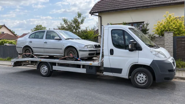 Bílý odtahový vůz s upevněným vozidlem Škoda na hliníkové plošině