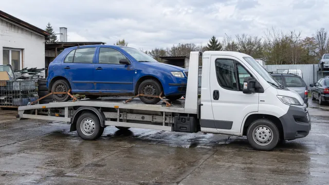 Bílý odtahový vůz s upevněným vozidlem Škoda na hliníkové plošině