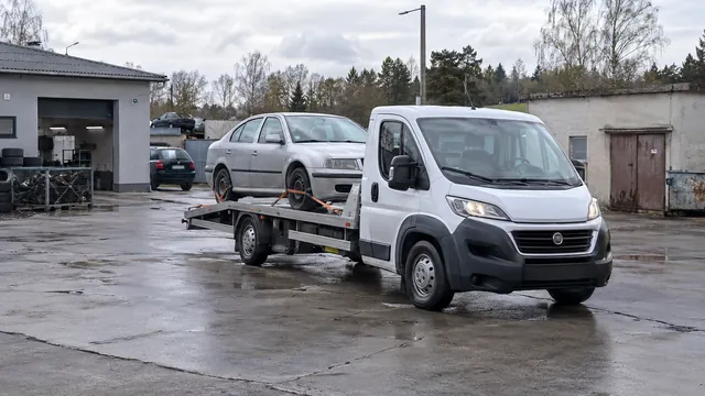Bílý odtahový vůz s upevněným vozidlem Škoda na hliníkové plošině